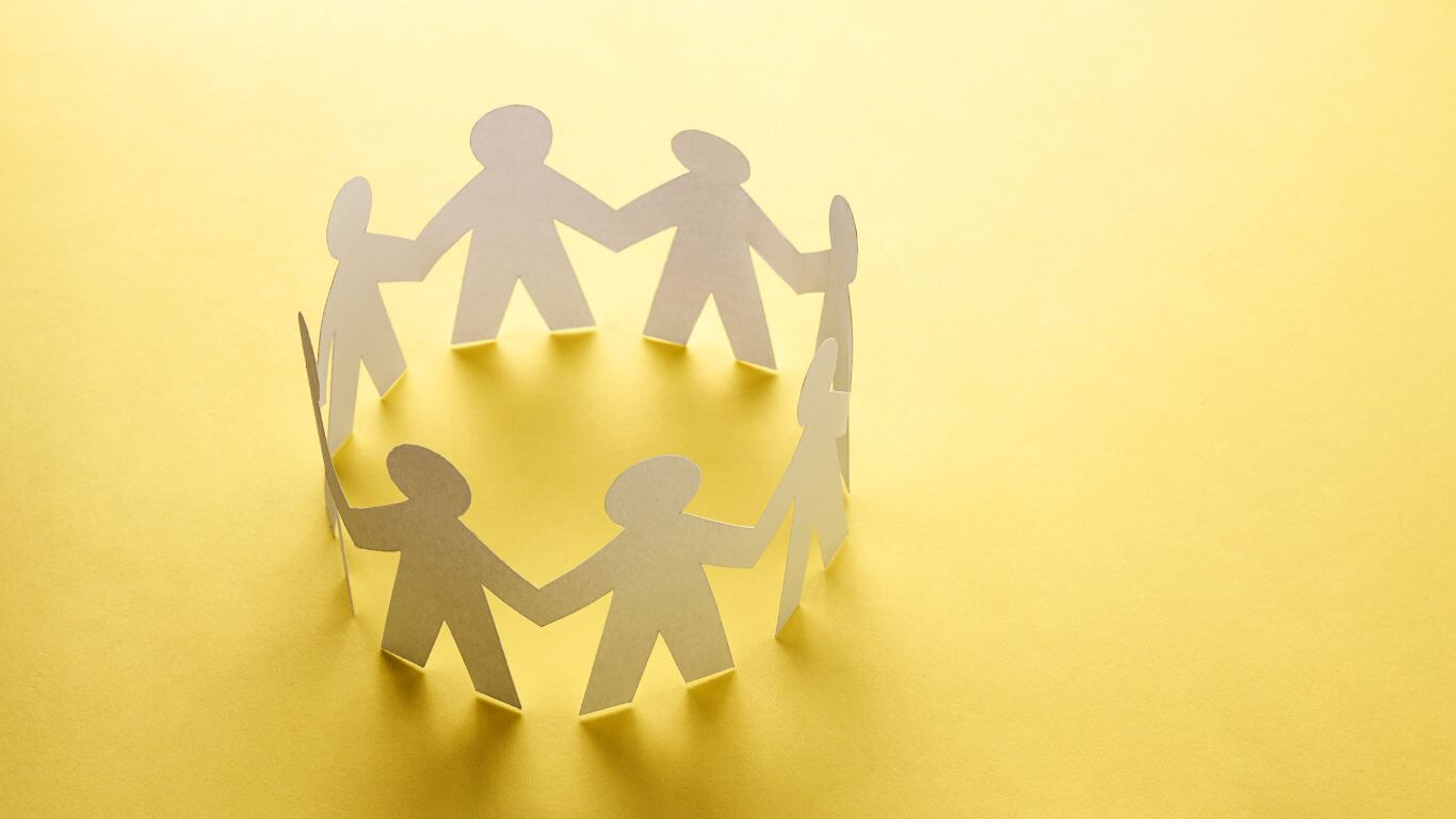 Photo of paper cut-out people in a circle, all holding hands