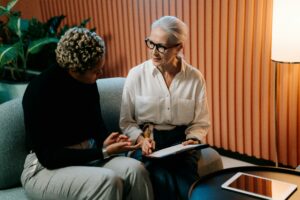 Senior leader practising compassionate leadership by actively listening to a colleague during a supportive one-to-one meeting, highlighting emotional intelligence, empathy in management, and the importance of psychological safety in the workplace.